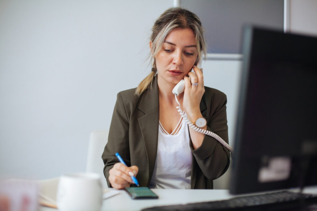 Könyvelő telefonon egyeztet ügyféllel az irodában