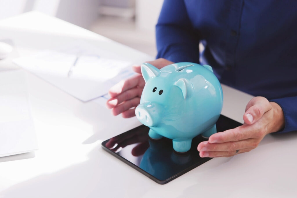 Kék persely malac egy irodai asztalon – a bevétel és profit közötti különbség szemléltetése.