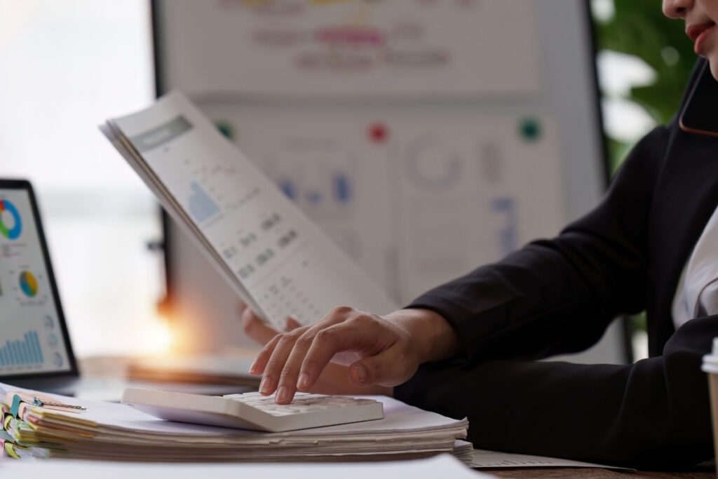 Könyvelő pénzügyi kimutatásokat elemez, miközben számológépet használ