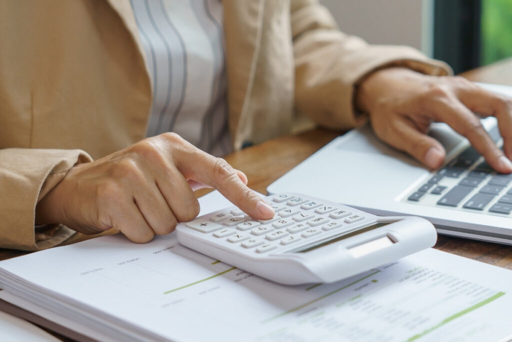 Könyvelő számológéppel és laptoppal dolgozik – pénzügyi kimutatás készítése.