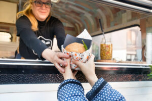 Mozgó vendéglátó egység hamburgert ad át egy vásárlónak